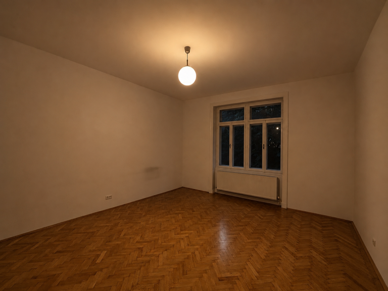 Leerer Altbau-Raum in Wien mit Fischgrät-Parkett und einer einzelnen Pendelleuchte – fehlende Lichtplanung macht den Raum dunkel und klein